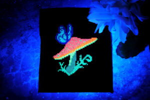 A glow in the dark cross stitch of a mushroom and butterfly under blacklight.