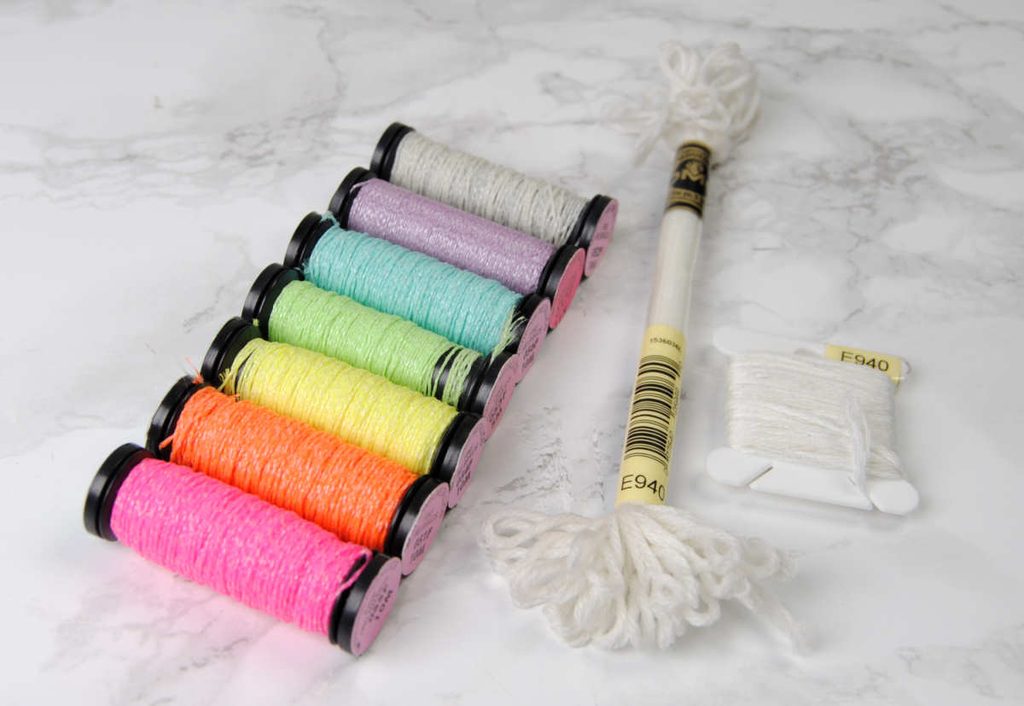 Comparing glow in the dark thread side by side of Kreinik spools and DMC on skein and bobbin 