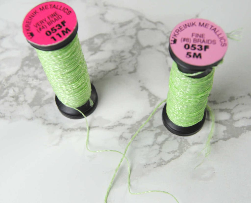 Two spools of green kreinik glow in the dark thread, one in #4 and one in #8 to show size difference.