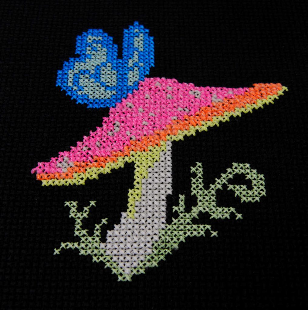 Photo of a glow in the dark cross stitch with the lights on