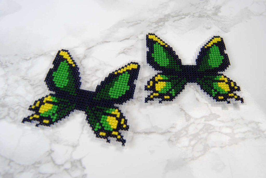 Two cross stitched butterflies on plastic canvas, cut to shape.