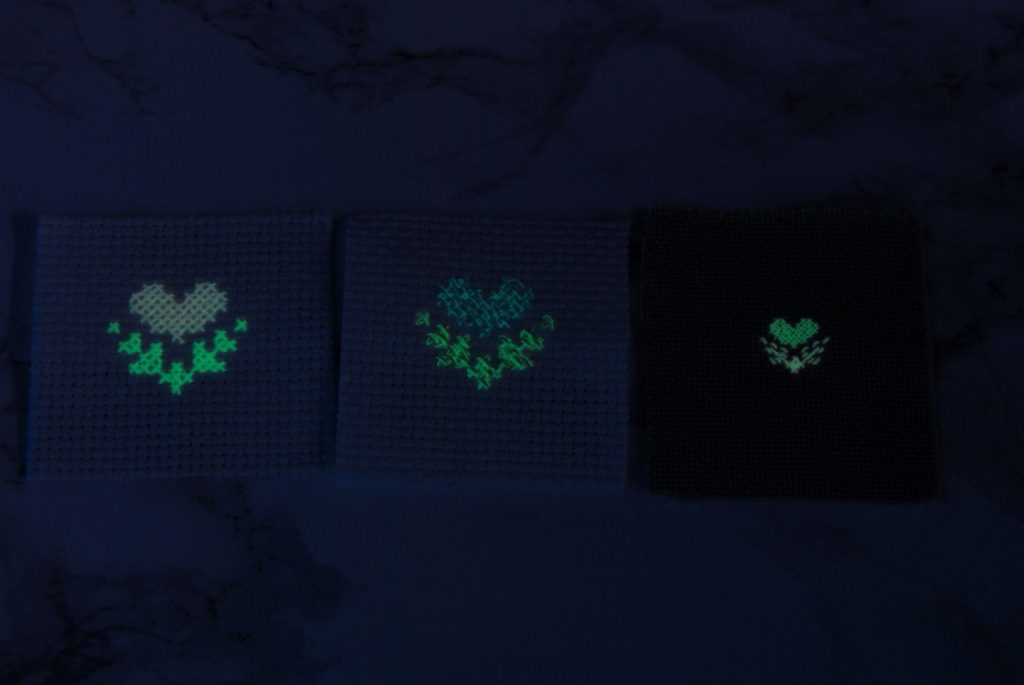 Three similar designs stitched on different fabric counts with different strand counts to show case coverage. In the dark.