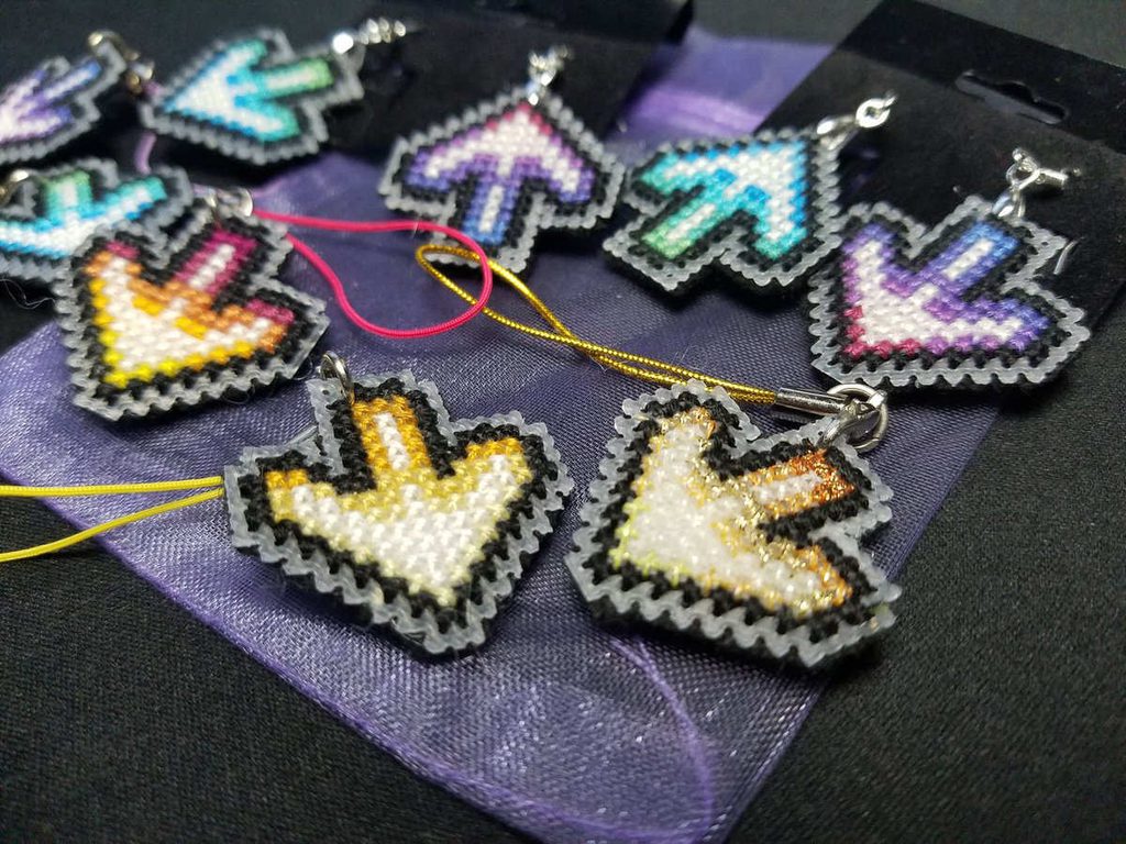 Closeup of some cross stitched DDR arrows turned into keychains and earrings.