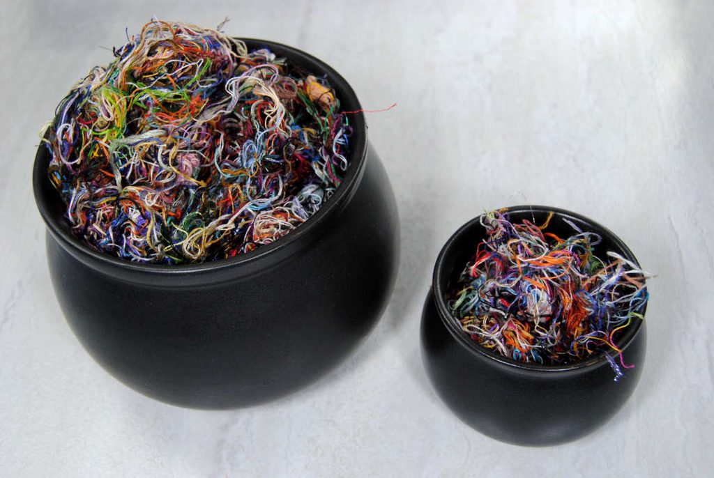 Two ceramic cauldrons, one large one small, both full of leftover thread orts.