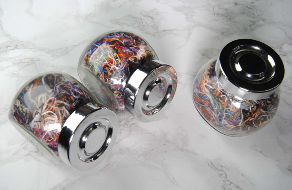 Small spice jars full of a jumble of colorful ORT threads