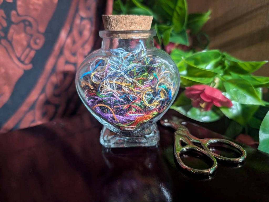A small heart shaped jar full of ort threads.