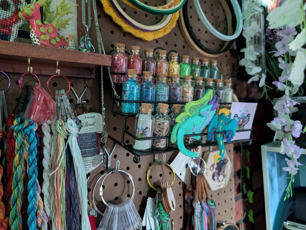 A pegboard wall with thread on floss drops and in tiny jars.