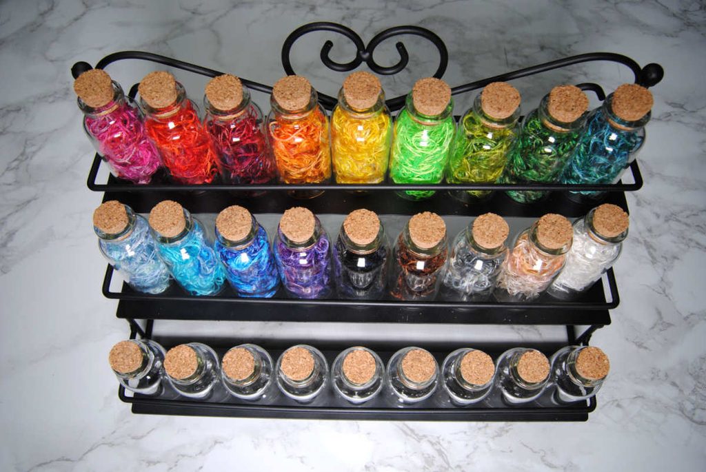 A nail polish holder repurposed to hold small potion bottles full of colorful thread.