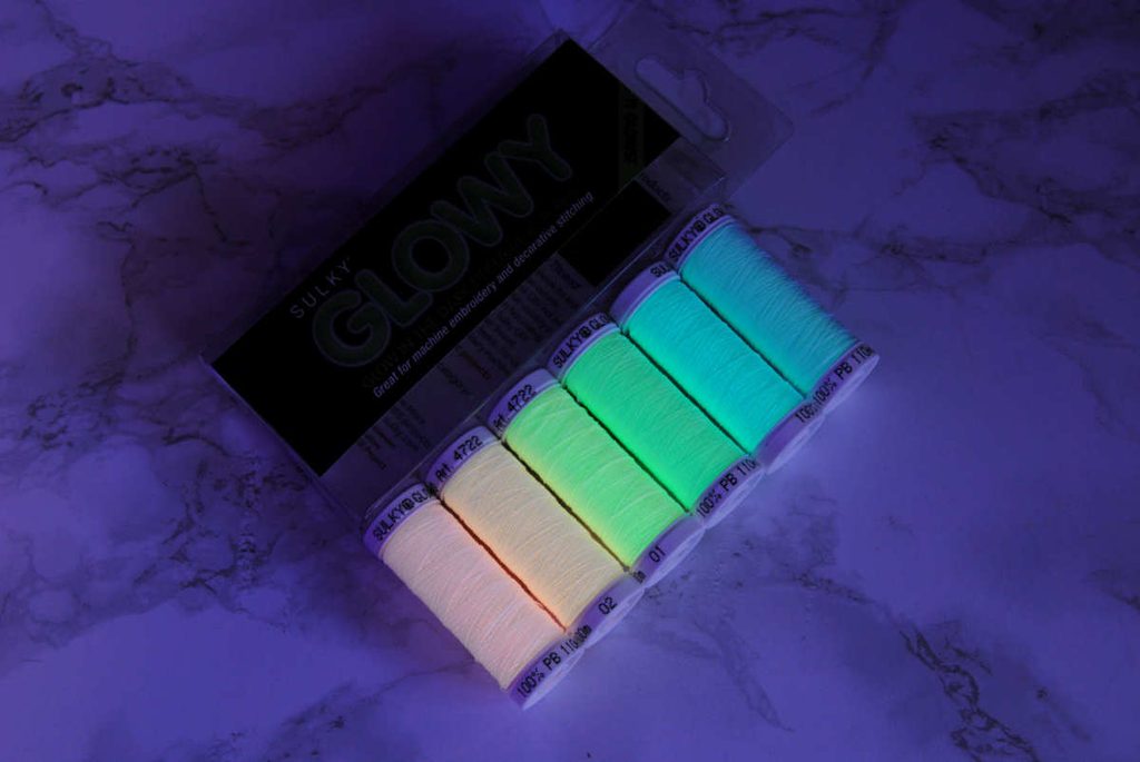 Sulky Glowy brand thread spools glowing in low ambient lighting after charging.