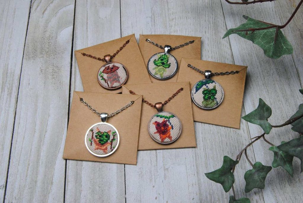 Cross stitched Koroks from the Legend of Zelda series made into pendant necklaces.