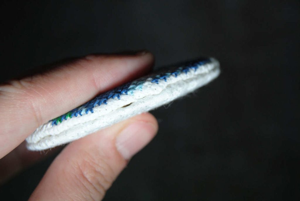 Side view of two fabric discs ladder stitched together.