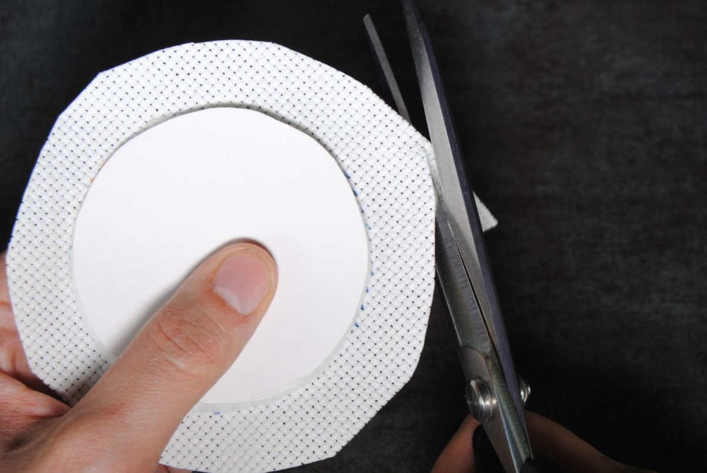 Trimming aida to about half an inch larger than a cardstock circle