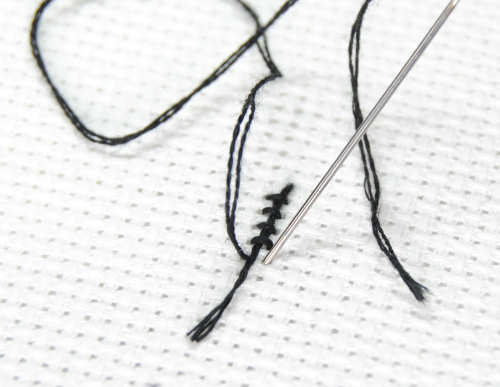 Continue stitching over your thread tail as you cross stitch your first several stitches.