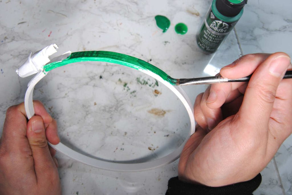 Applying metallic acrylic paint onto the primed wooden embroidery hoop.