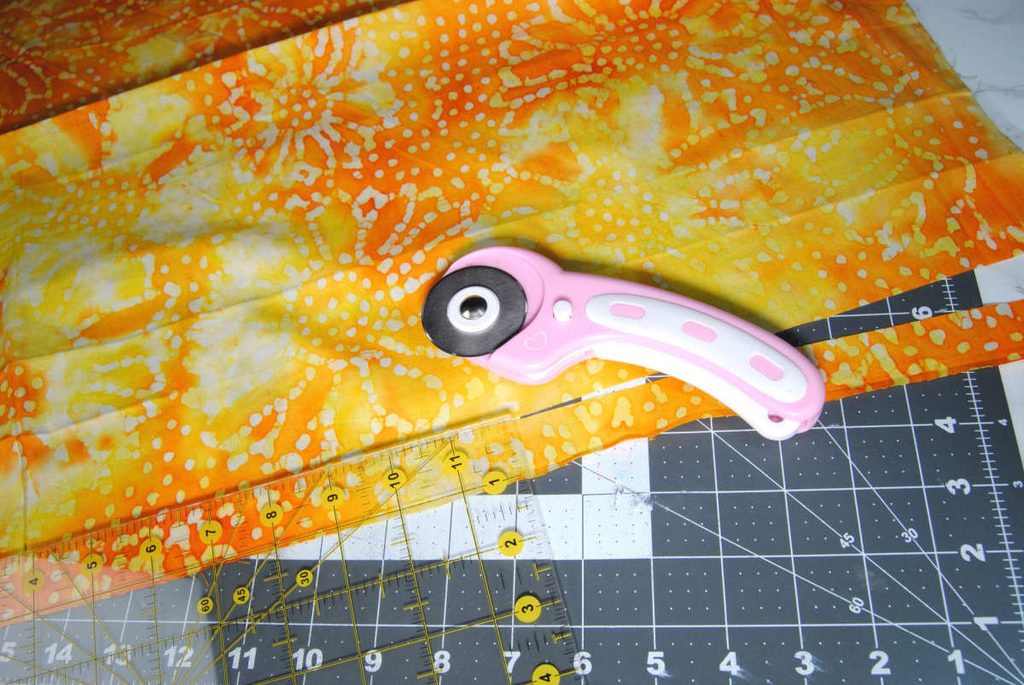 Using a rotary cutter to cut a 1" strip of fabric