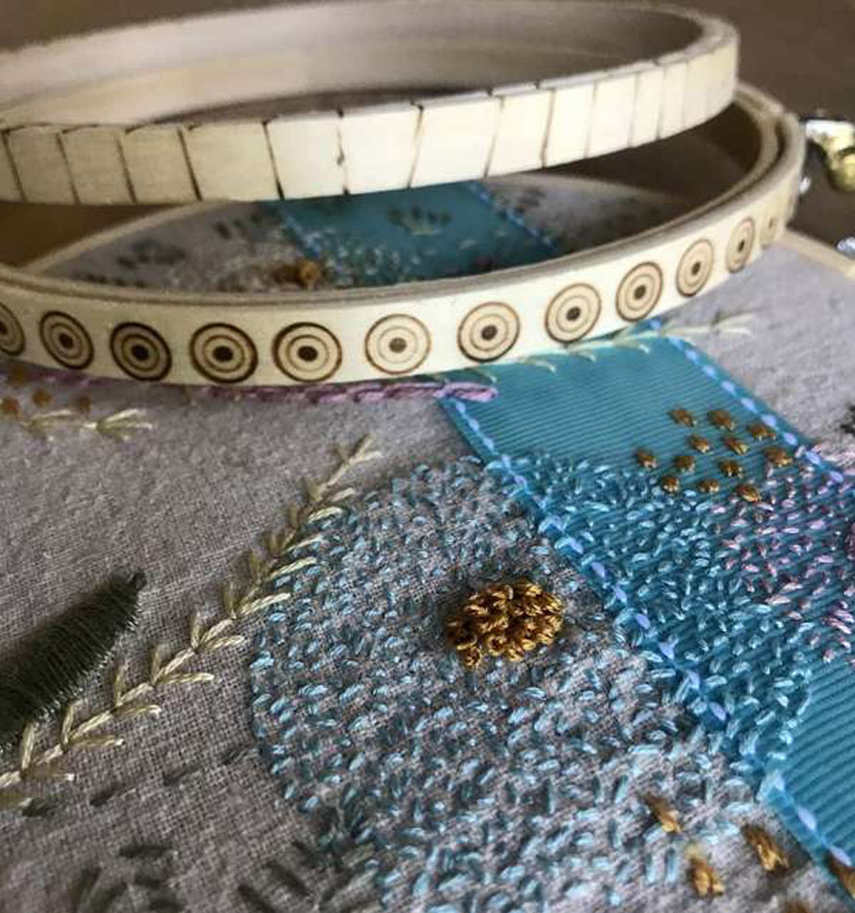Two embroidery hoops with wood burned designs along the side.