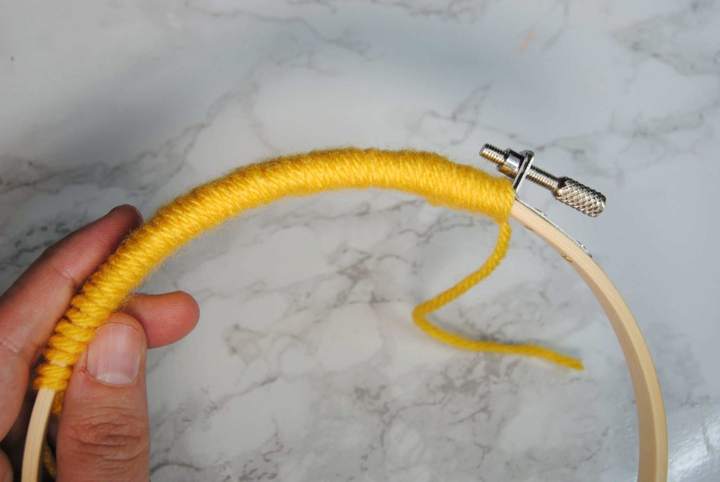 Yarn tightly wrapped around the side of an embroidery hoop.