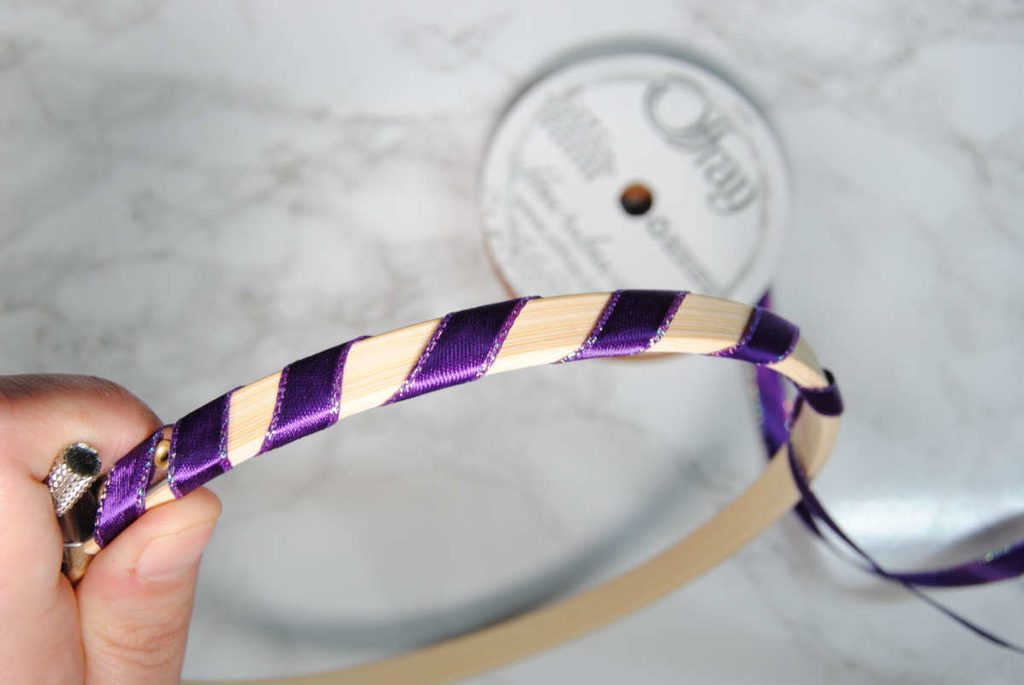 Spacing out ribbon wrapping along an embroidery hoop to create a candy cane effect.