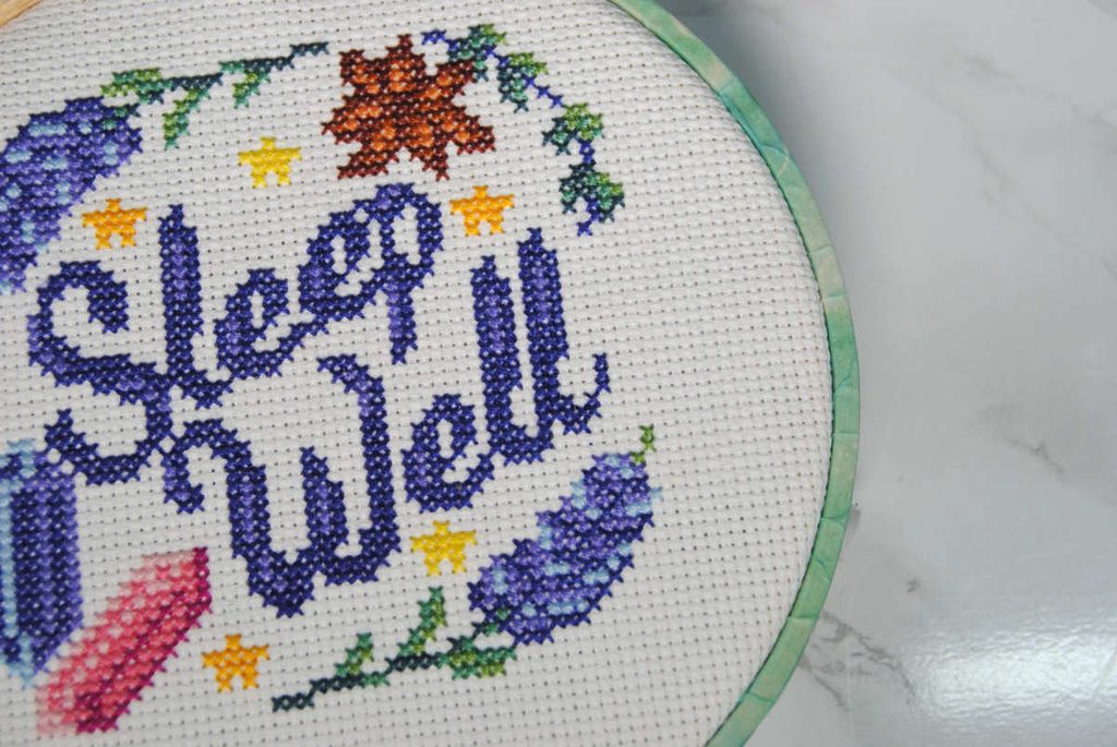 A cross stitch project in an embroidery hoop embellished with washi tape wrapped around the outer edge.