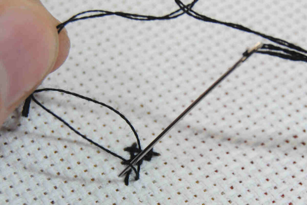 Demonstration of splitting threads to railroad cross stitches.
