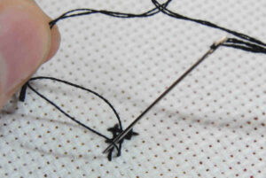 Demonstration of splitting a thread to railroad cross stitches.
