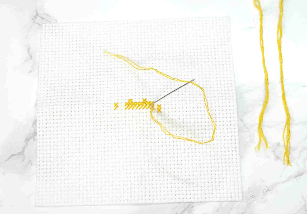 The beginning of a cross stitch being stitched in Mouliné Étoile C444