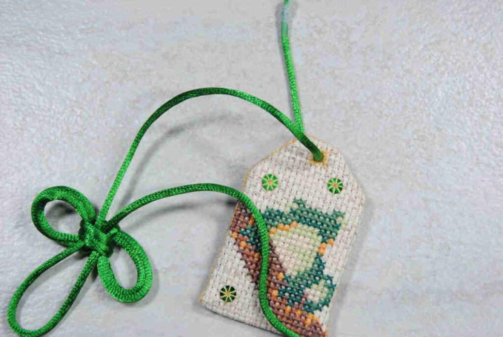Feed omamori knot cording through the eyelet of your stitched piece.