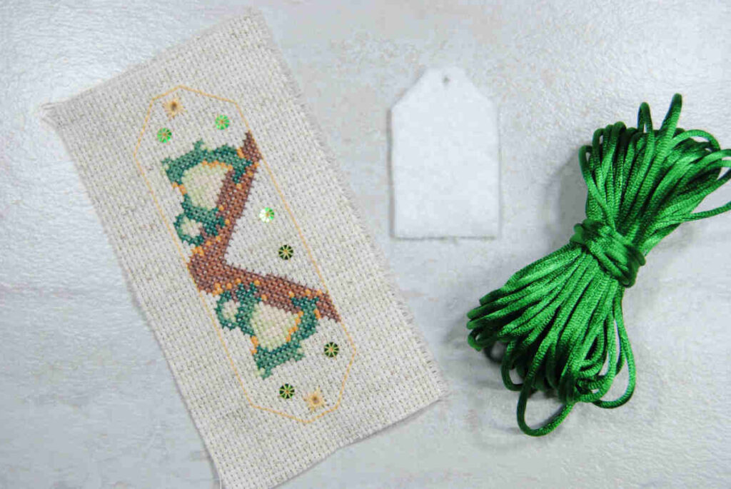 Materials needed for a cross stitch omamori charm.