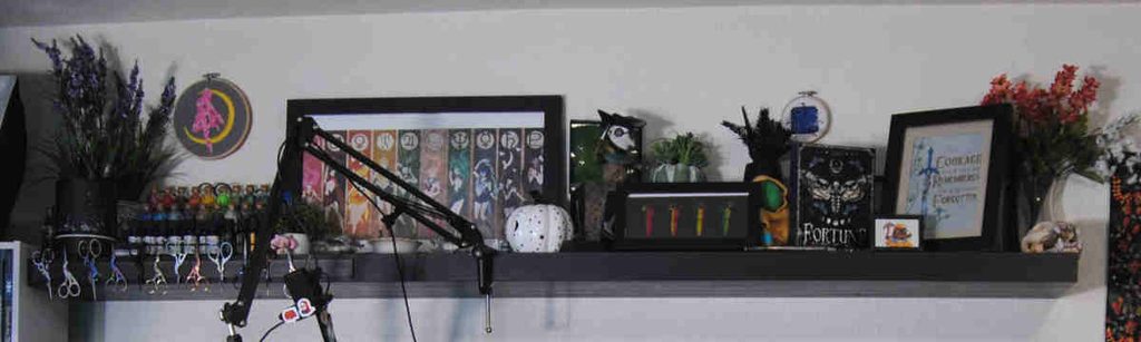 Wall shelf covered in art, decor, and scissors.
