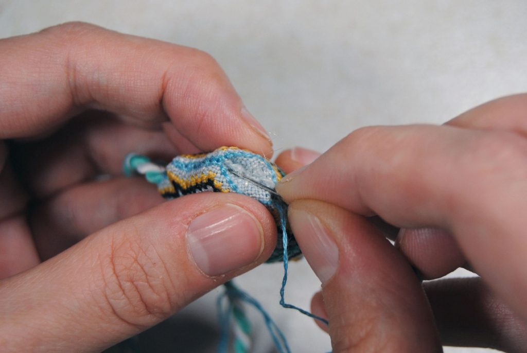 Using a needle to push fabric out of the way as you stitch.