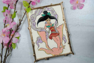 Cross stitch of Princess Sakuya from the game Okami, framed in a gold branch frame.