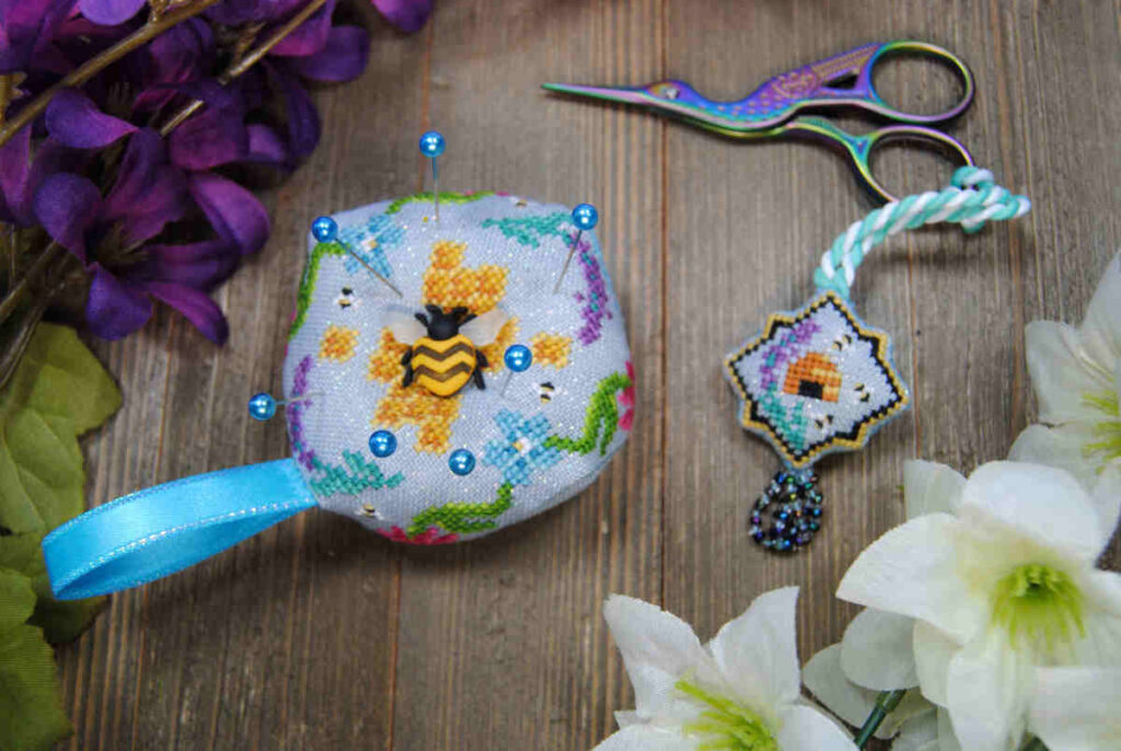 Cross stitch scissor fob and matching biscornu featuring beehive and lavender sprig with a beaded tassel