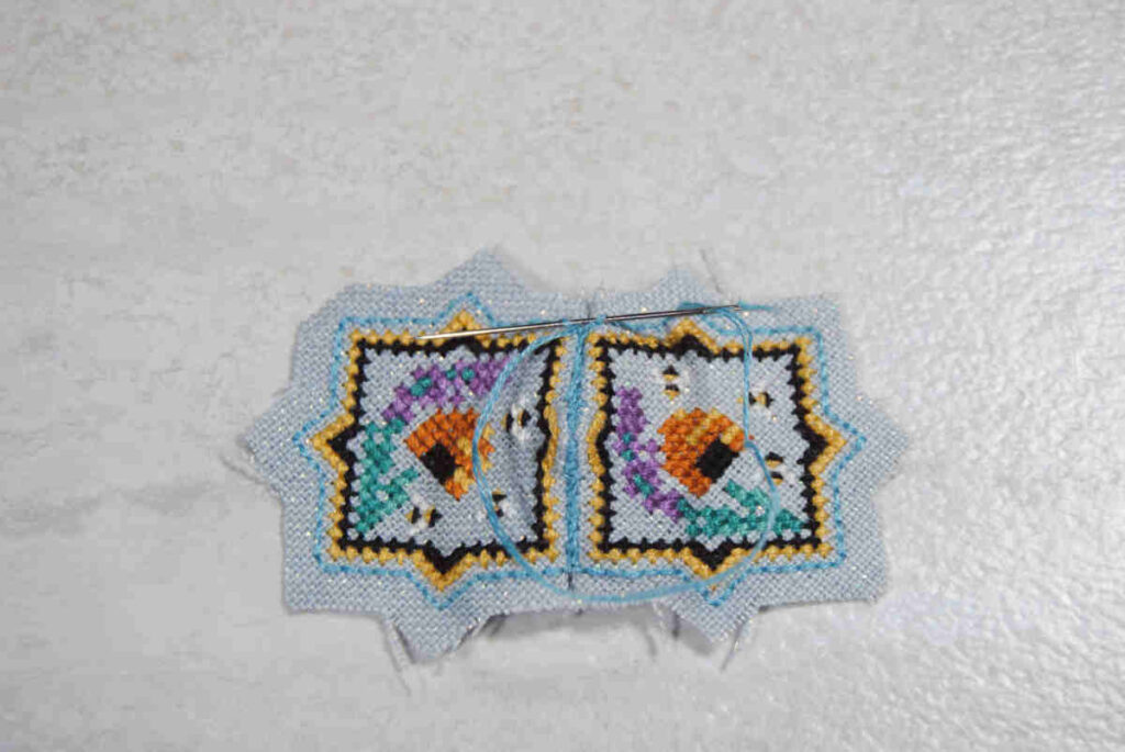 Demonstrating stitching two cross stitches together by sewing under the backstitch outlines.