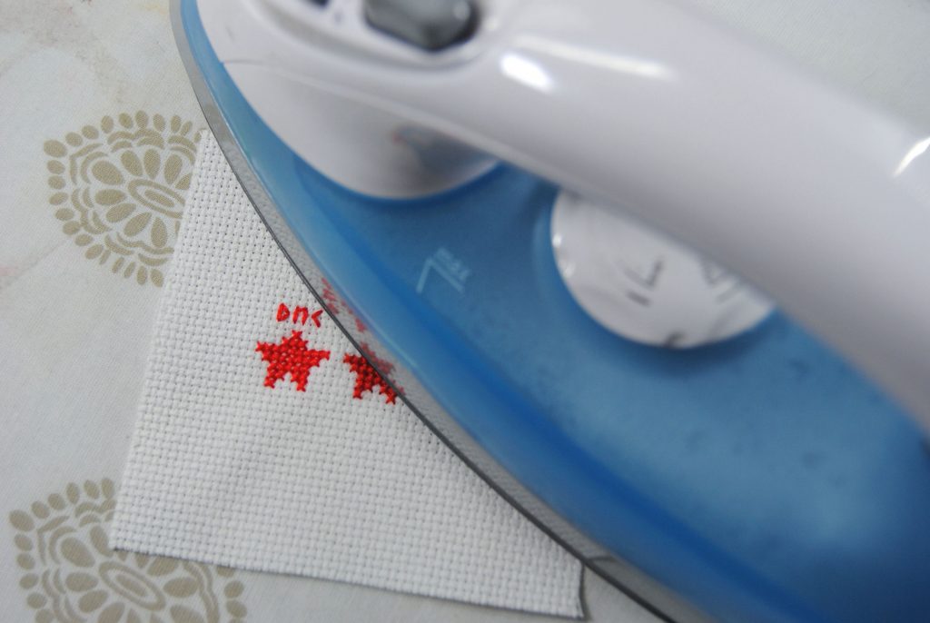 Ironing a cross stitch to test whether the thread is color fast.
