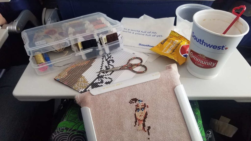In-flight photo of working on a cross stitch project on a plane.