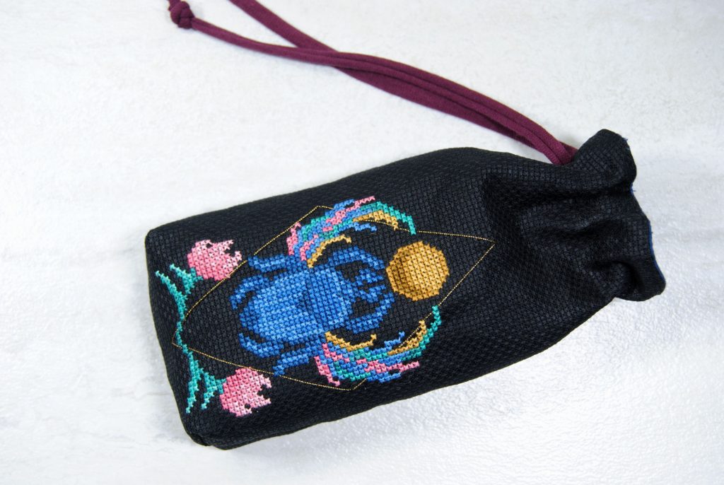 A finished cross stitch tarot bag